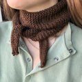 Person wearing a brown knitted scarf with a light green shirt